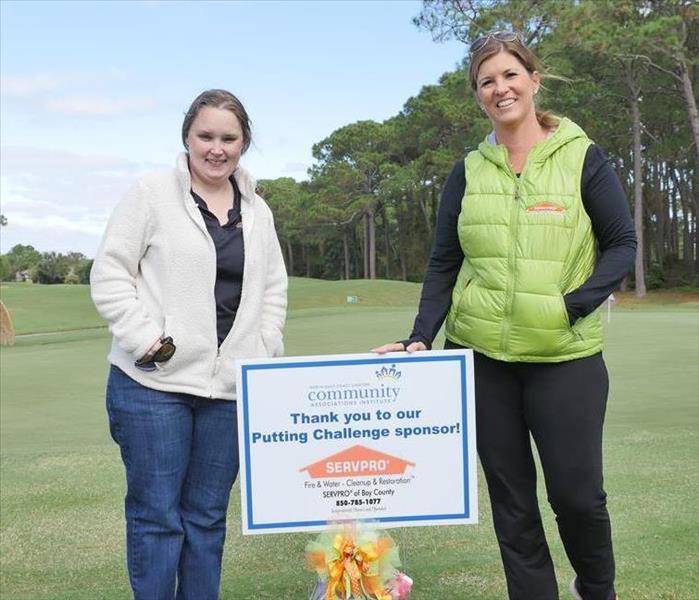 Two Women on a Golf Course with a Small Sign
