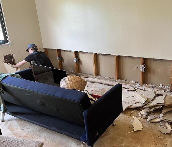 SERVPRO team member working on repairing water damage to an interior wall